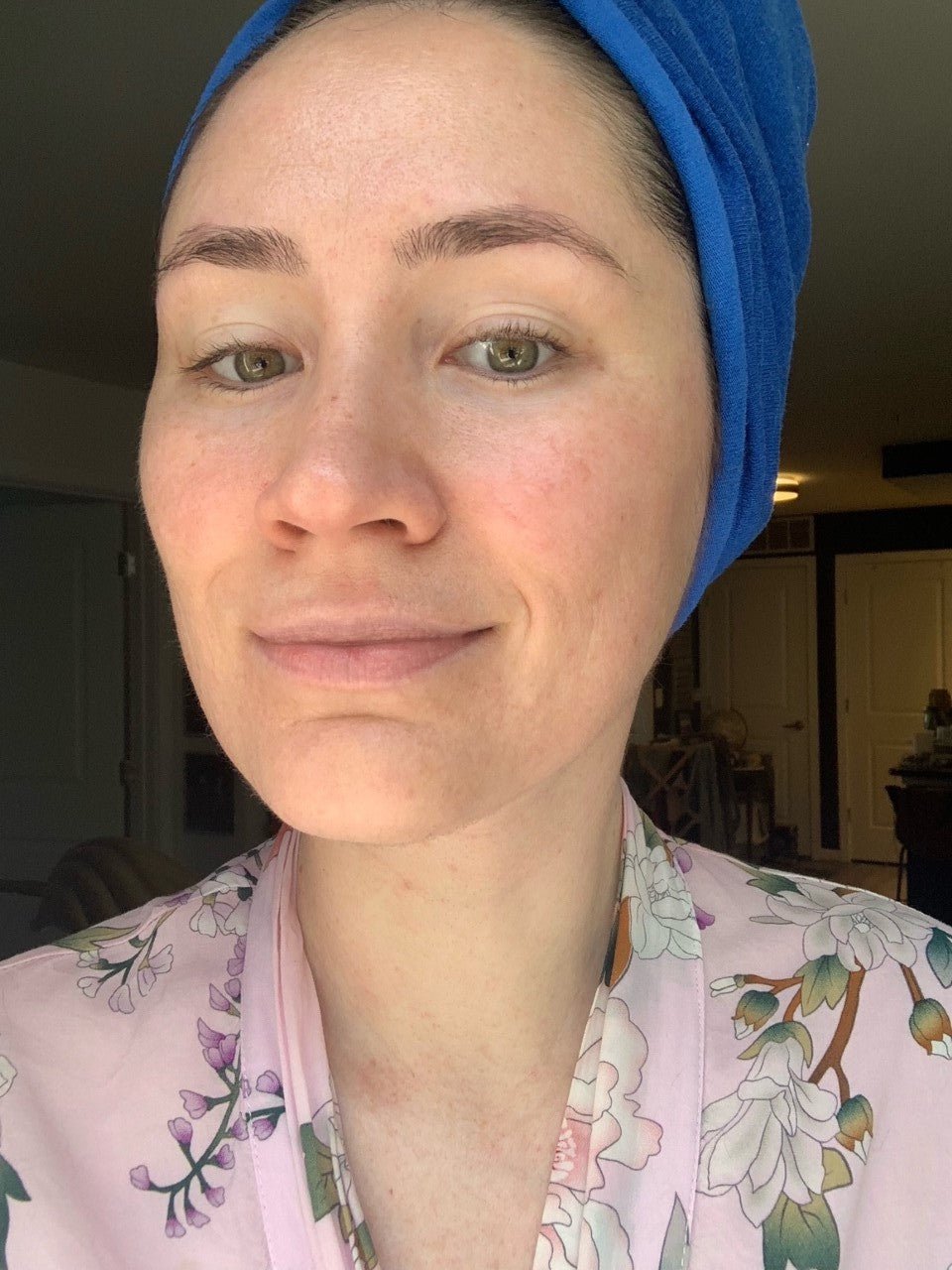 Person wearing a blue headscarf and floral pajama top indoors.