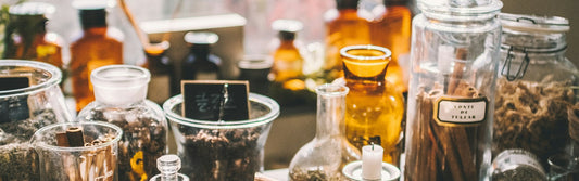 Dried herbs and botanicals in glass jars, laid out on a table