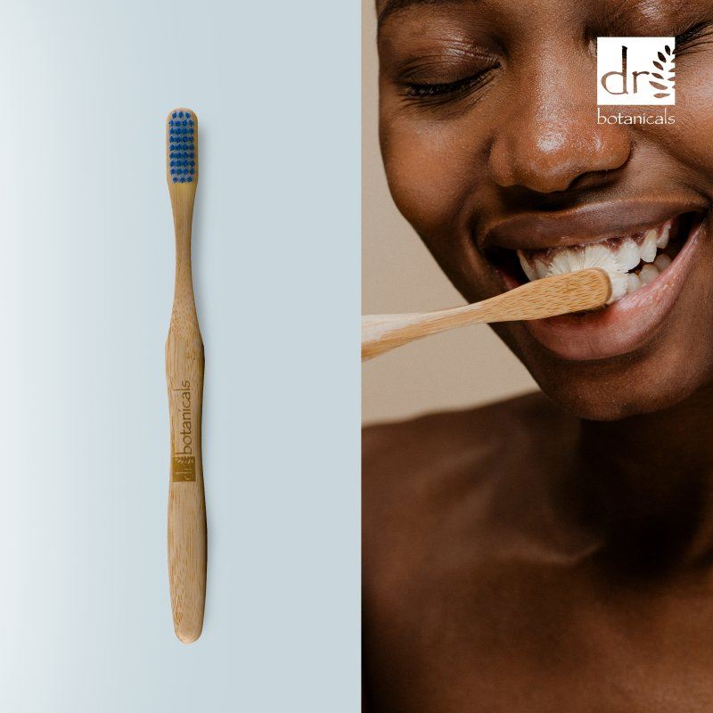 Dr Botanicals bamboo toothbrush with a person brushing their teeth on a light blue background