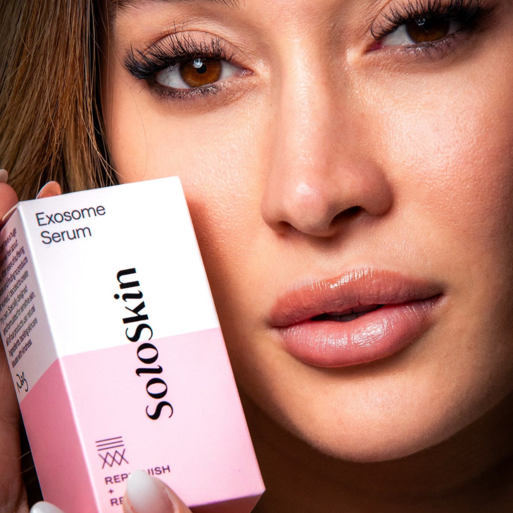 Close-up of a woman holding a pink 'soloskin' Exosome Serum box.
