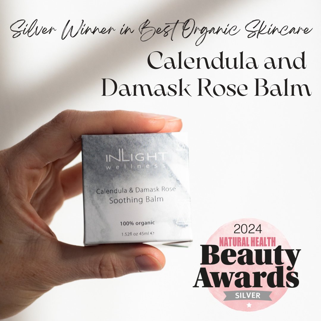Hand holding a box of Inlight Beauty Calendula & Damask Rose Soothing Balm 45ml with award text on a white background