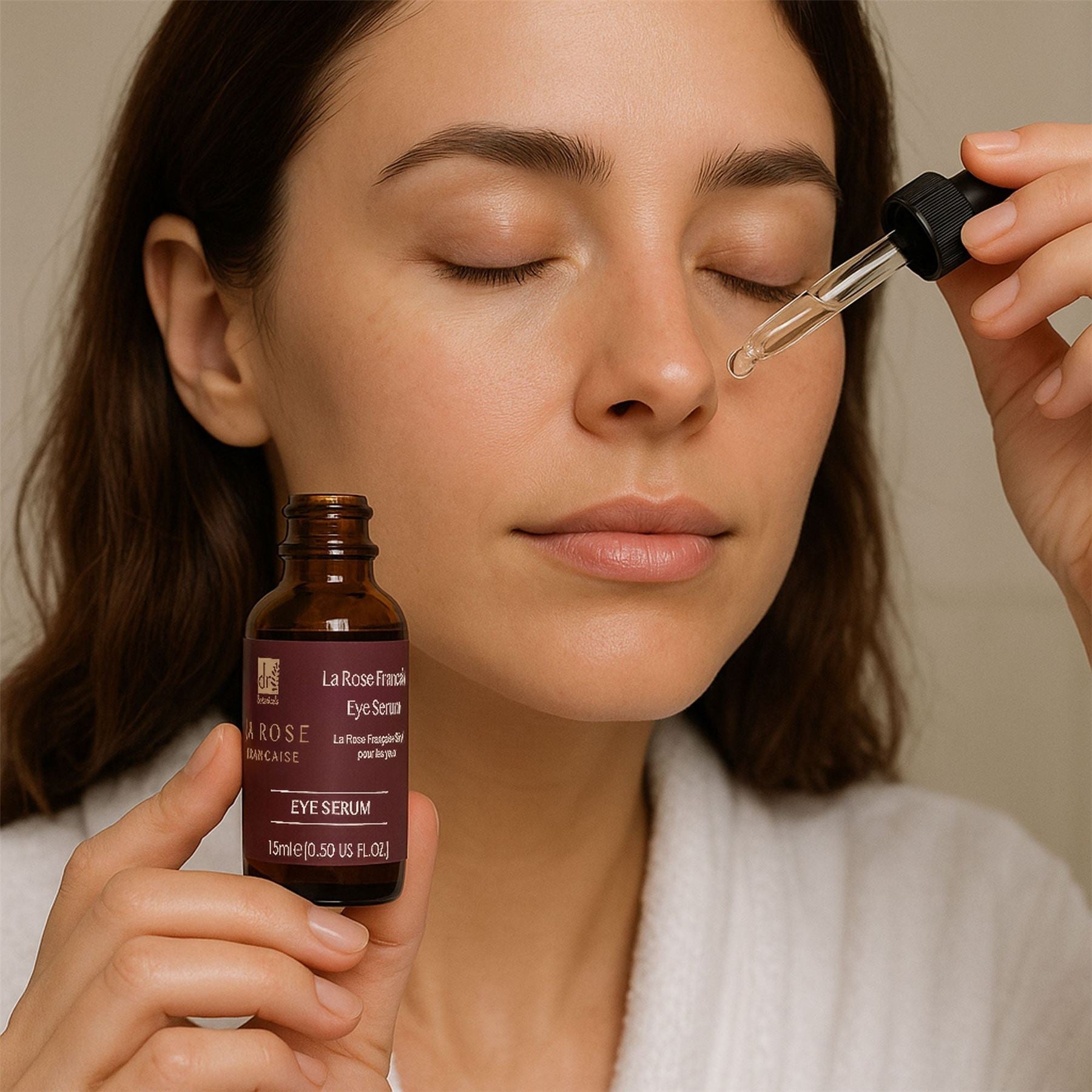 Woman applying eye serum with a dropper to her face, holding a bottle labeled 'La Rose Française'.