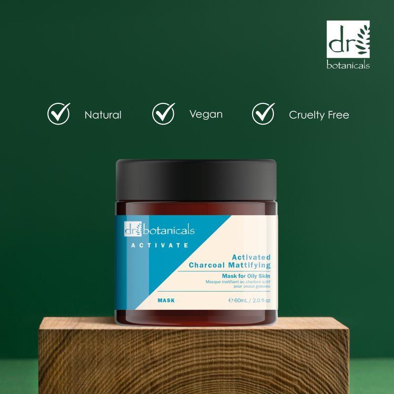Dr. Botanicals activated charcoal mask jar on a wooden block with green background