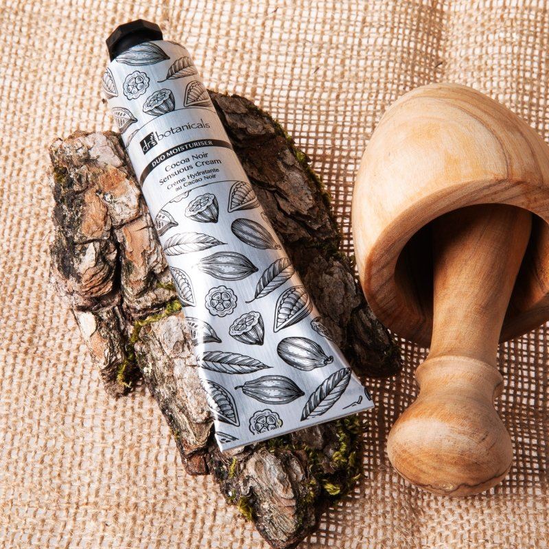 skinChemists Cocoa Noir Sensuous Cream on a wooden surface with a wooden pestle and mortar.