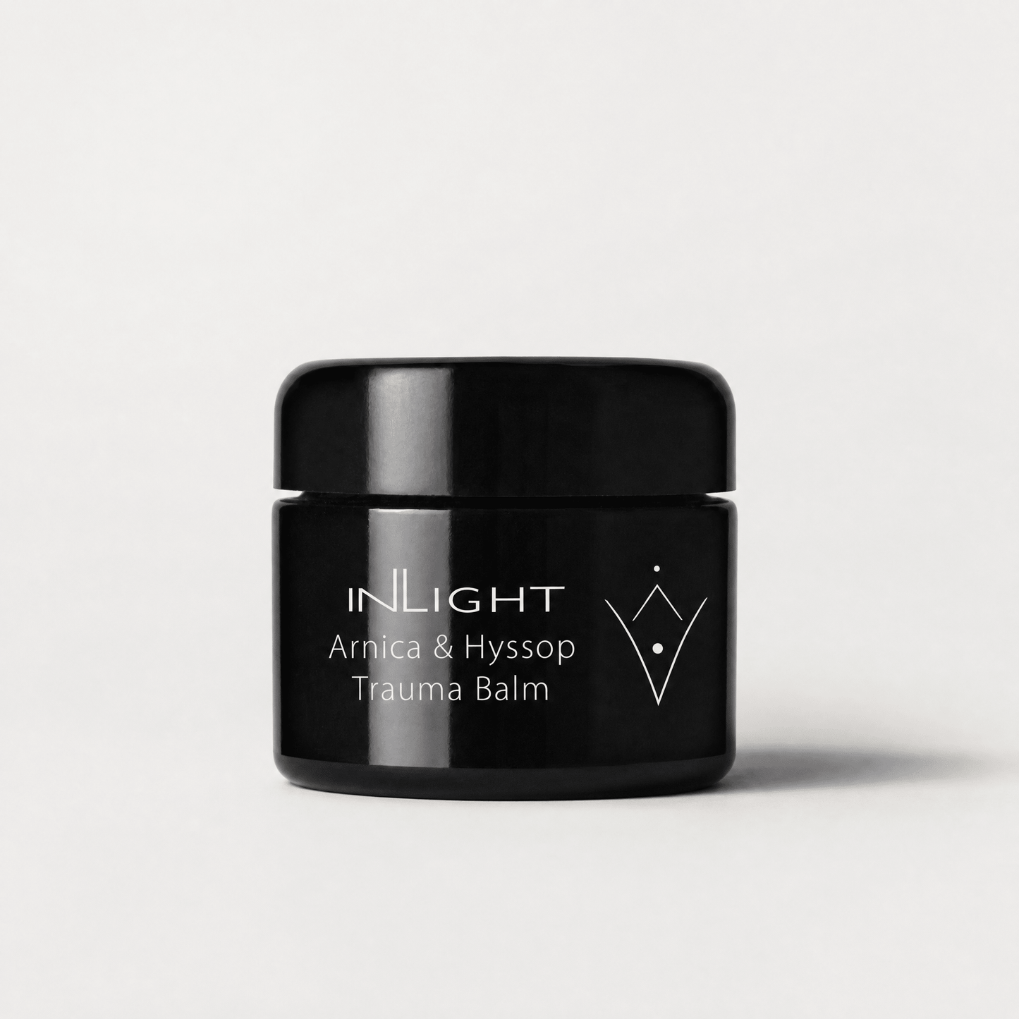 Black jar of Inlight Beauty Arnica & Hyssop Trauma Balm 45ml on a light grey background