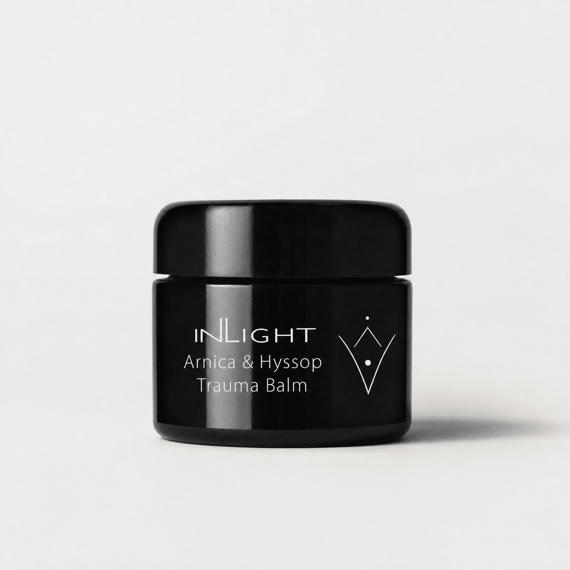 Black jar of Inlight Beauty Arnica & Hyssop Trauma Balm 45ml on a light grey background