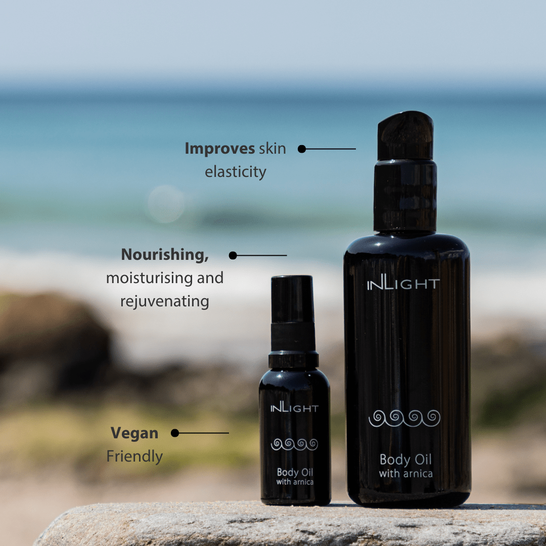 Two bottles of INLIGHT Body Oil with Arnica on a beach setting