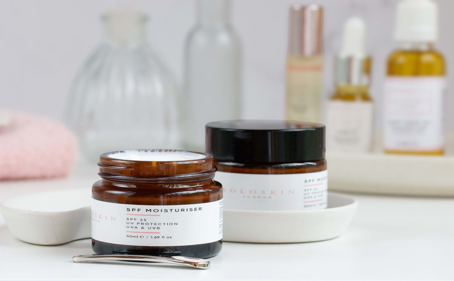 Two skincare jars on a white surface with blurred background