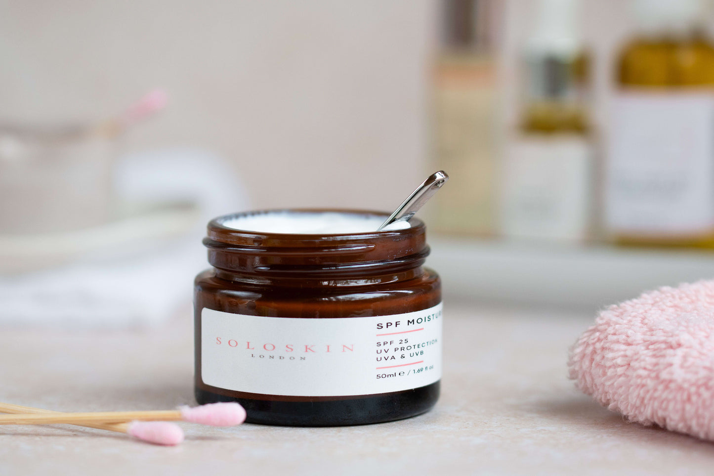 Jar of skincare product with a spoon inside on a bathroom counter
