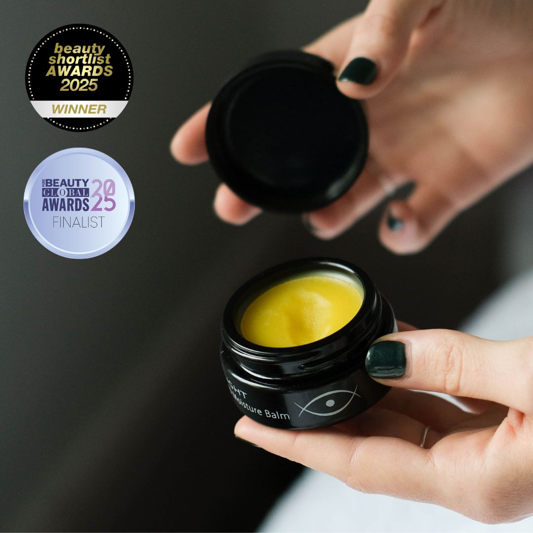 Person holding a black jar of Inlight Beauty Deep Moisture Balm 28ml with awards displayed above.