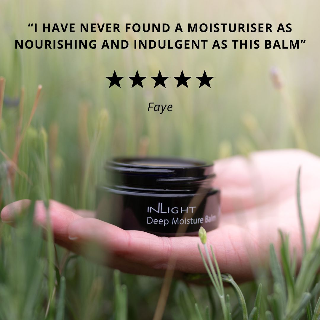 Hand holding a black jar of Inlight Beauty Deep Moisture Balm 28ml in grass with five-star rating and review text.