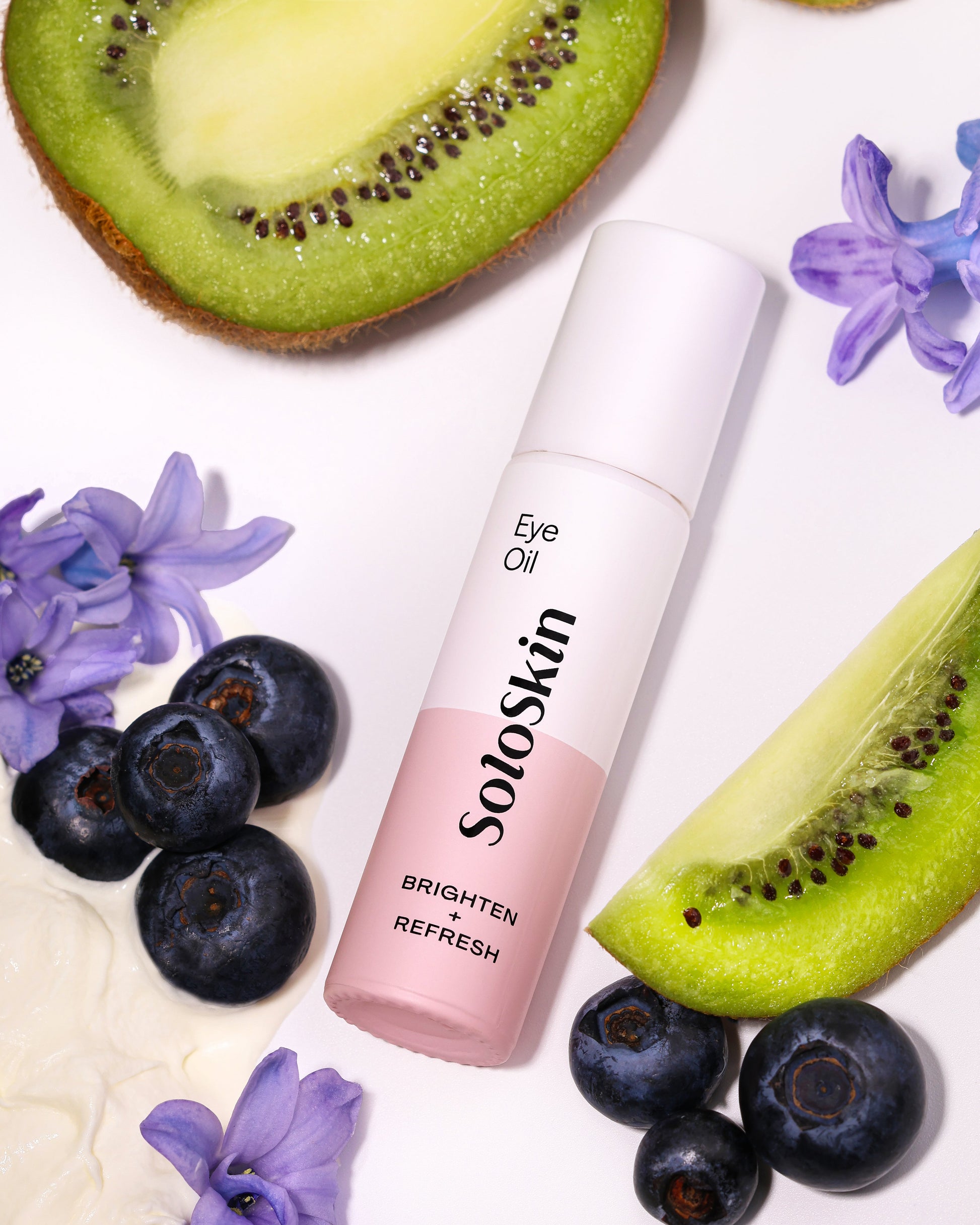 SoloSkin eye oil bottle with kiwis, blueberries, and flowers on a white background