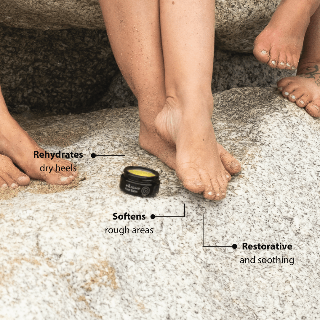 Person applying Inlight Beauty Foot Balm 45ml to dry feet with text indicating benefits on a stone surface.