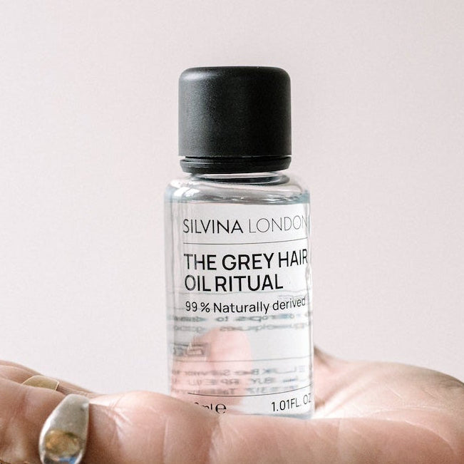 Silvina London hair oil bottle held in a hand with a neutral background