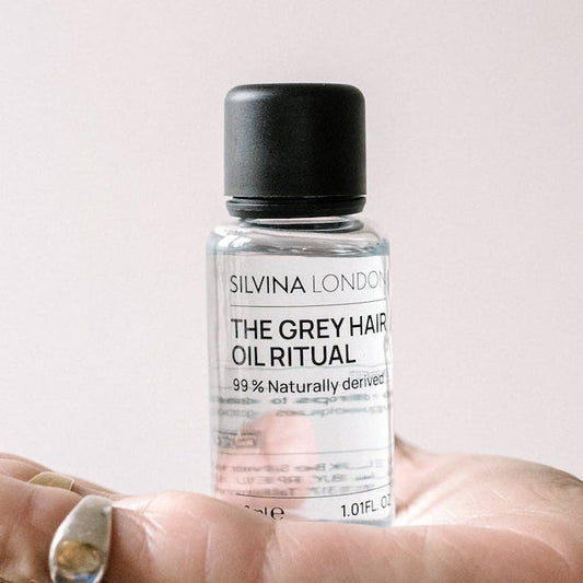 Silvina London hair oil bottle held in a hand with a neutral background