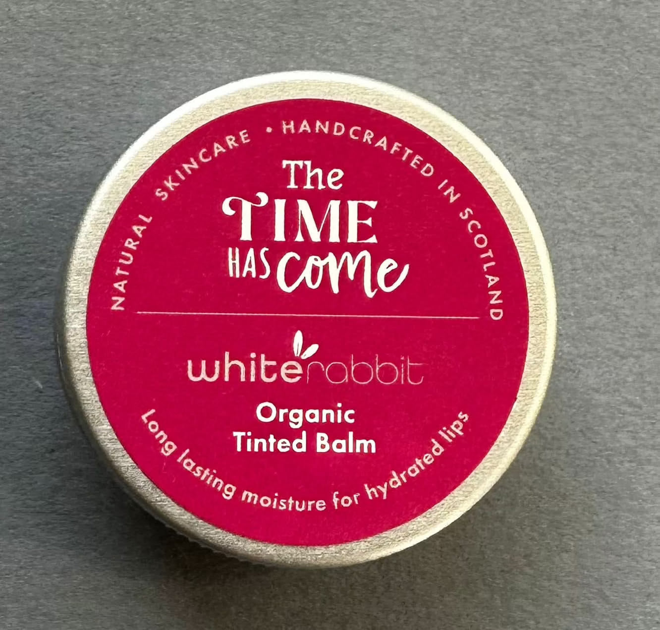 White Rabbit Organic Tinted Balm container on a grey background