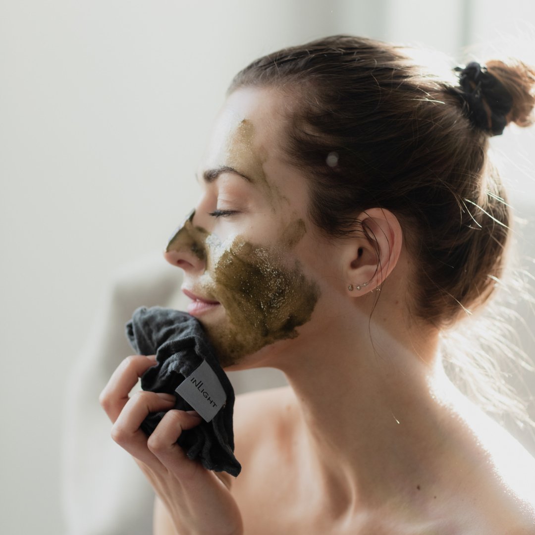Woman applying Inlight Beauty Super-Food Mask 25ml to her face with a towel.