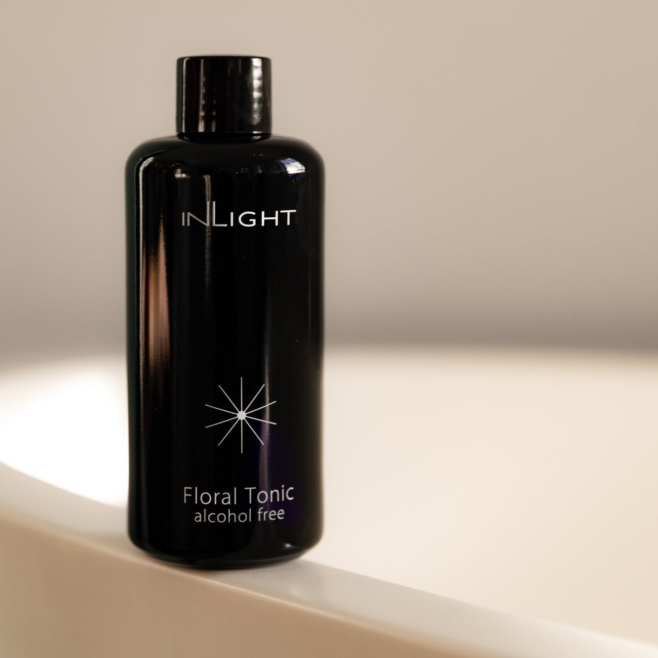 Black bottle of Inlight Beauty Floral Tonic 200ml on a beige background