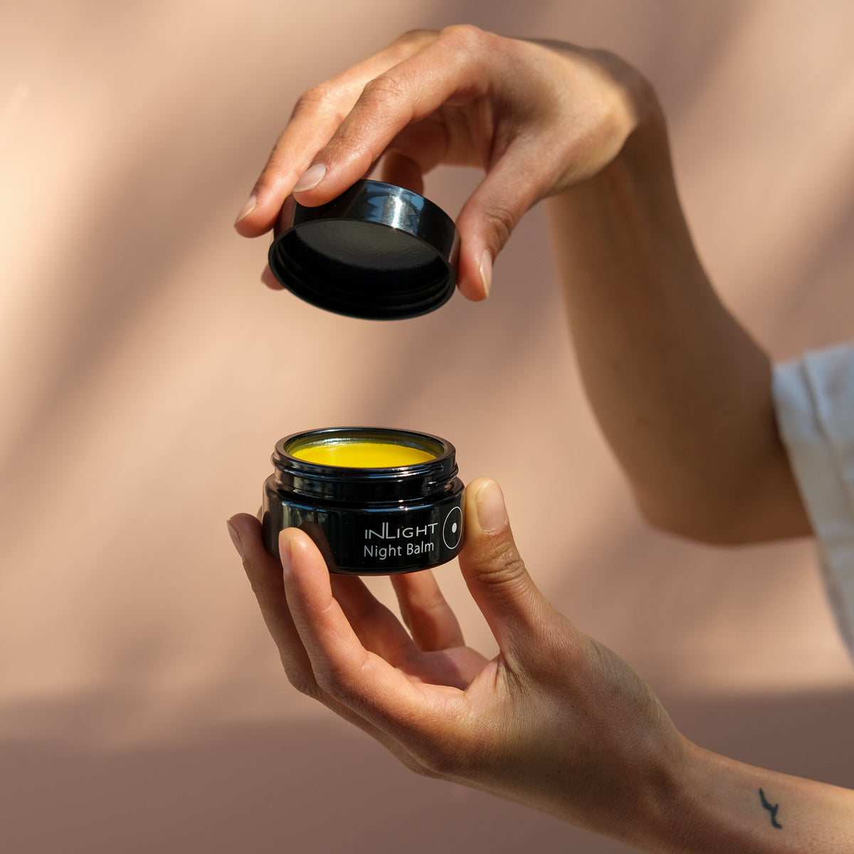 Person holding a jar of Inlight Beauty Night Balm 45ml with a blurred background