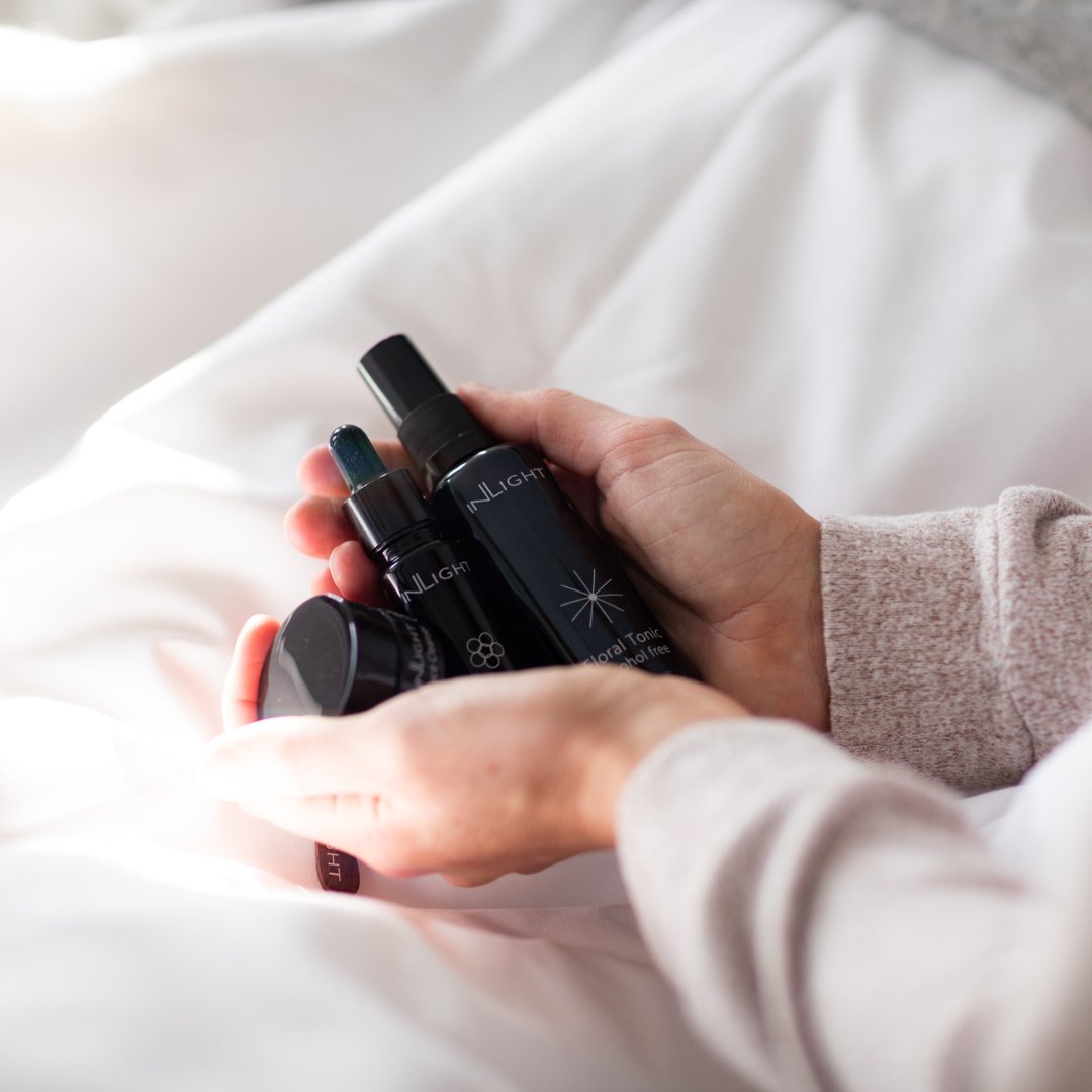 Hand holding Inlight Beauty Skincare Essential Set products with a blurred background