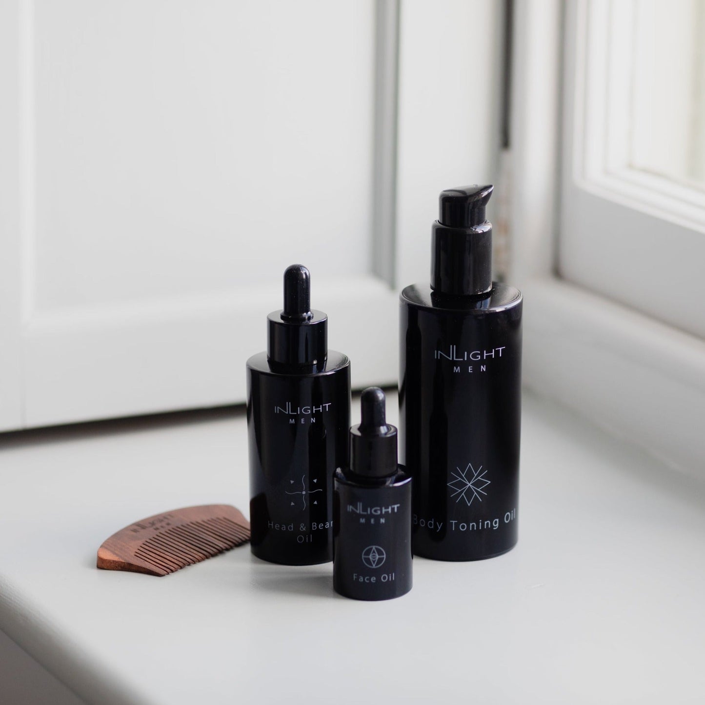 Three black skincare bottles labeled 'INLIGHT' on a windowsill.