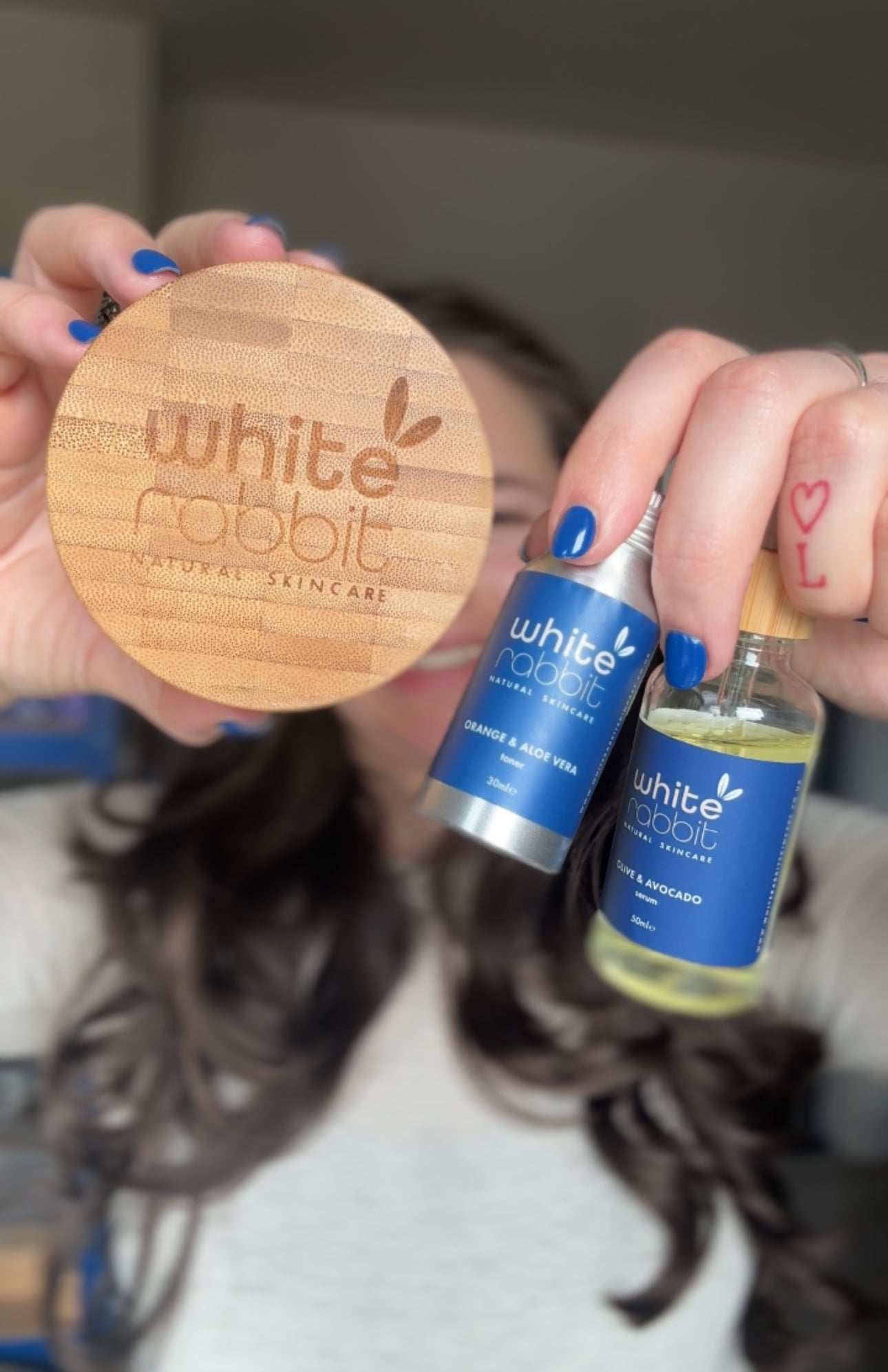 Person holding a wooden pot and two small bottles labelled 'White Rabbit' with hair in the background.