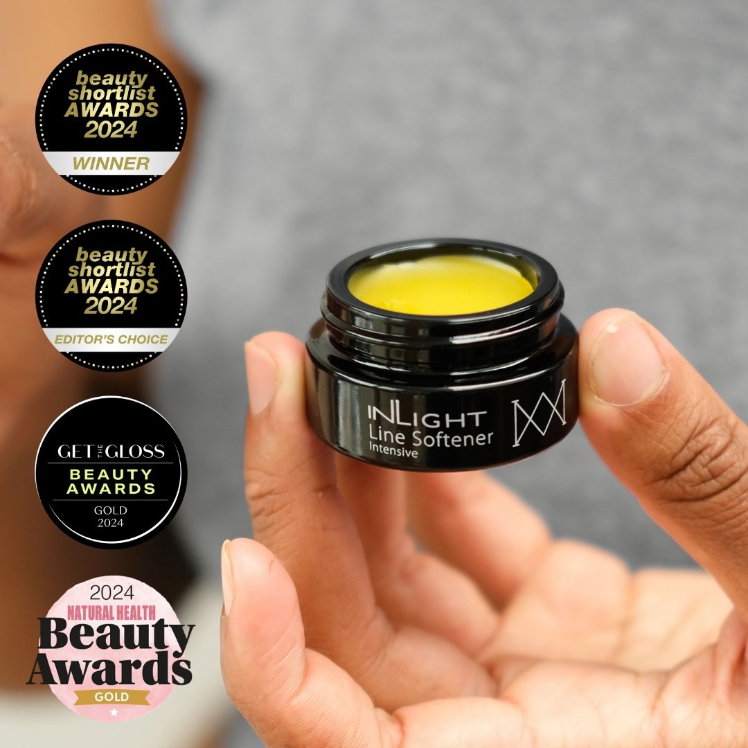 Hand holding a black jar of Inlight Beauty Line Softener Intensive 15ml with awards displayed on a blurred background