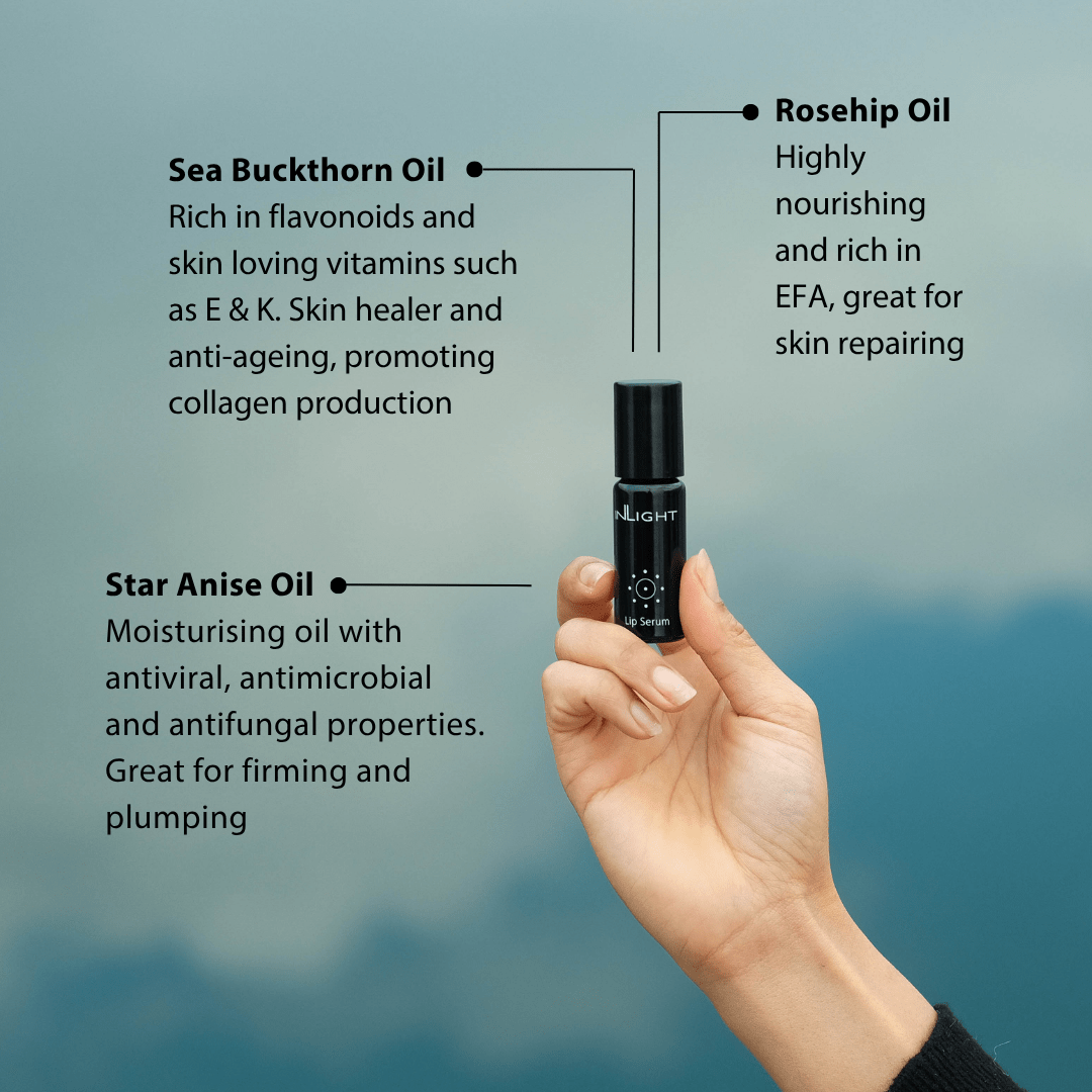 Hand holding a small black bottle of Inlight Beauty Lip Serum 10ml with text about Sea Buckthorn Oil, Rosehip Oil, and Star Anise Oil on a blue background.