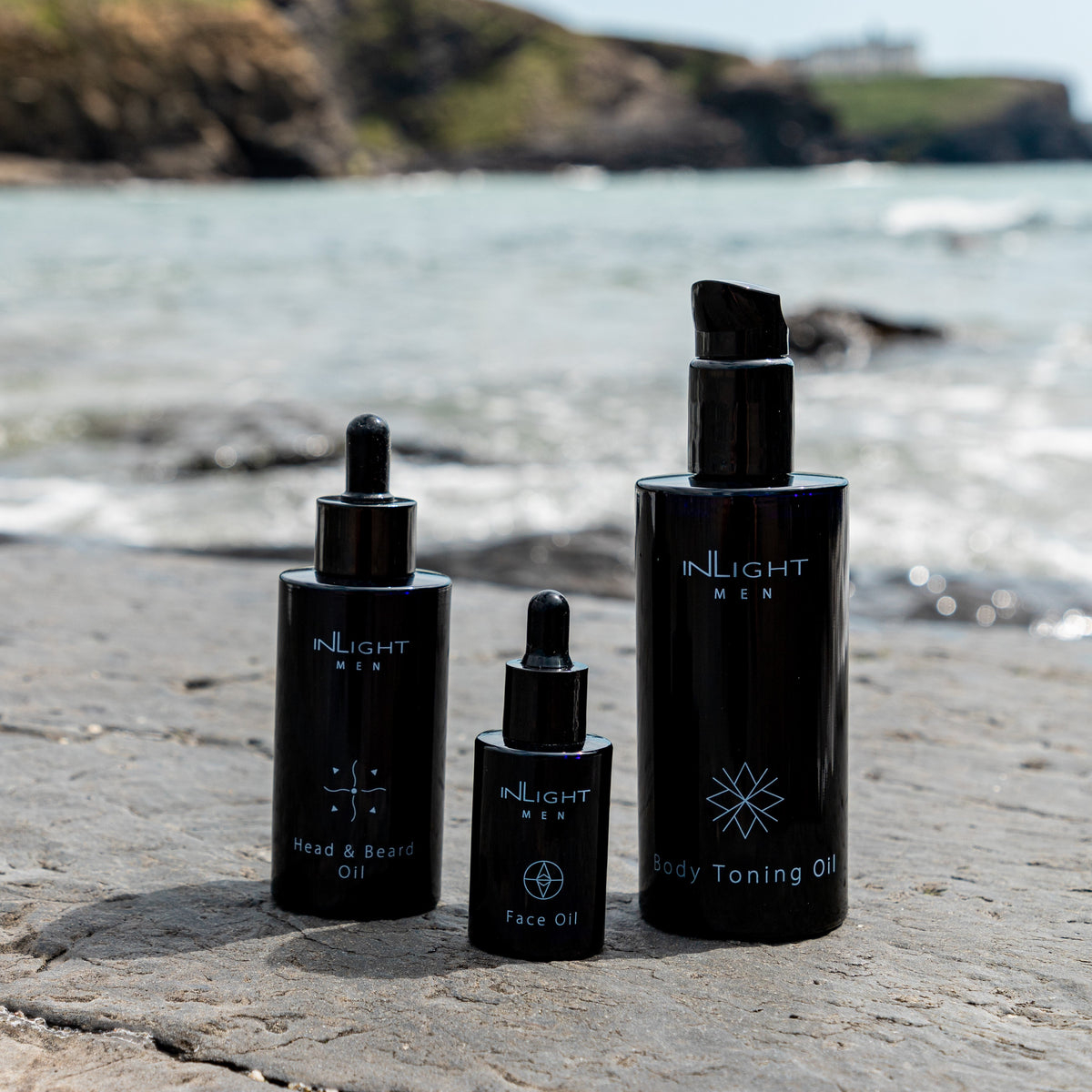 Set of skincare products from INLIGHT on a beach with ocean and cliffs in the background