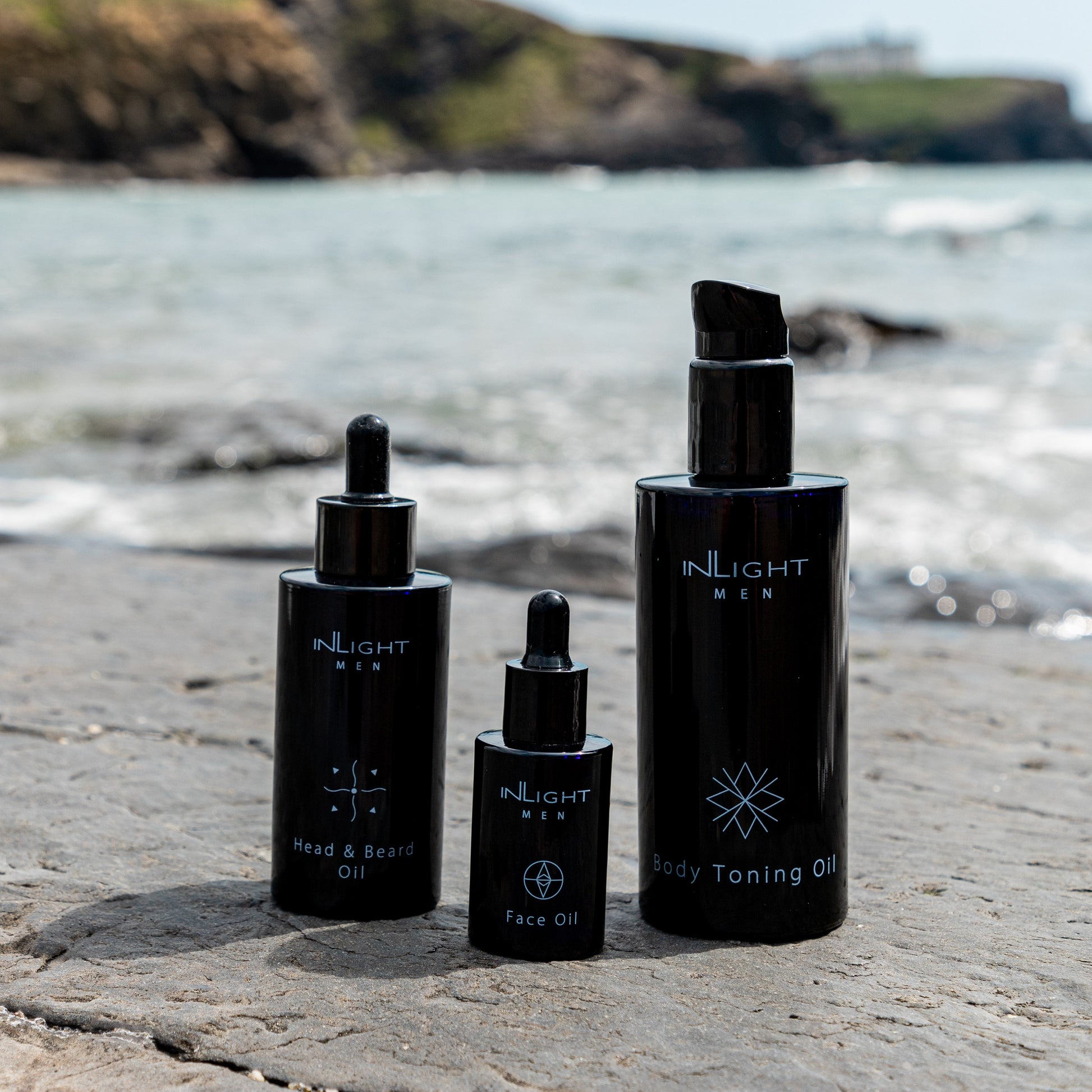 Set of skincare products from INLIGHT on a beach with ocean and cliffs in the background