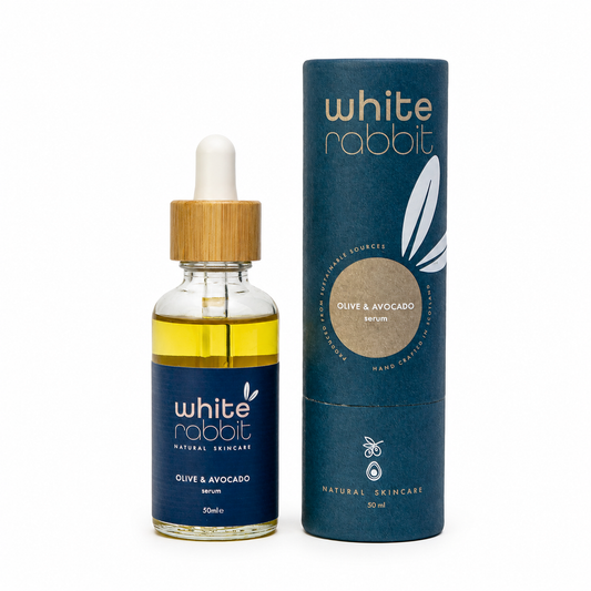 White Rabbit Olive & Avocado serum in a 50ml glass dropper bottle with a bamboo cap, shown next to its navy blue cylindrical packaging box on a white background.