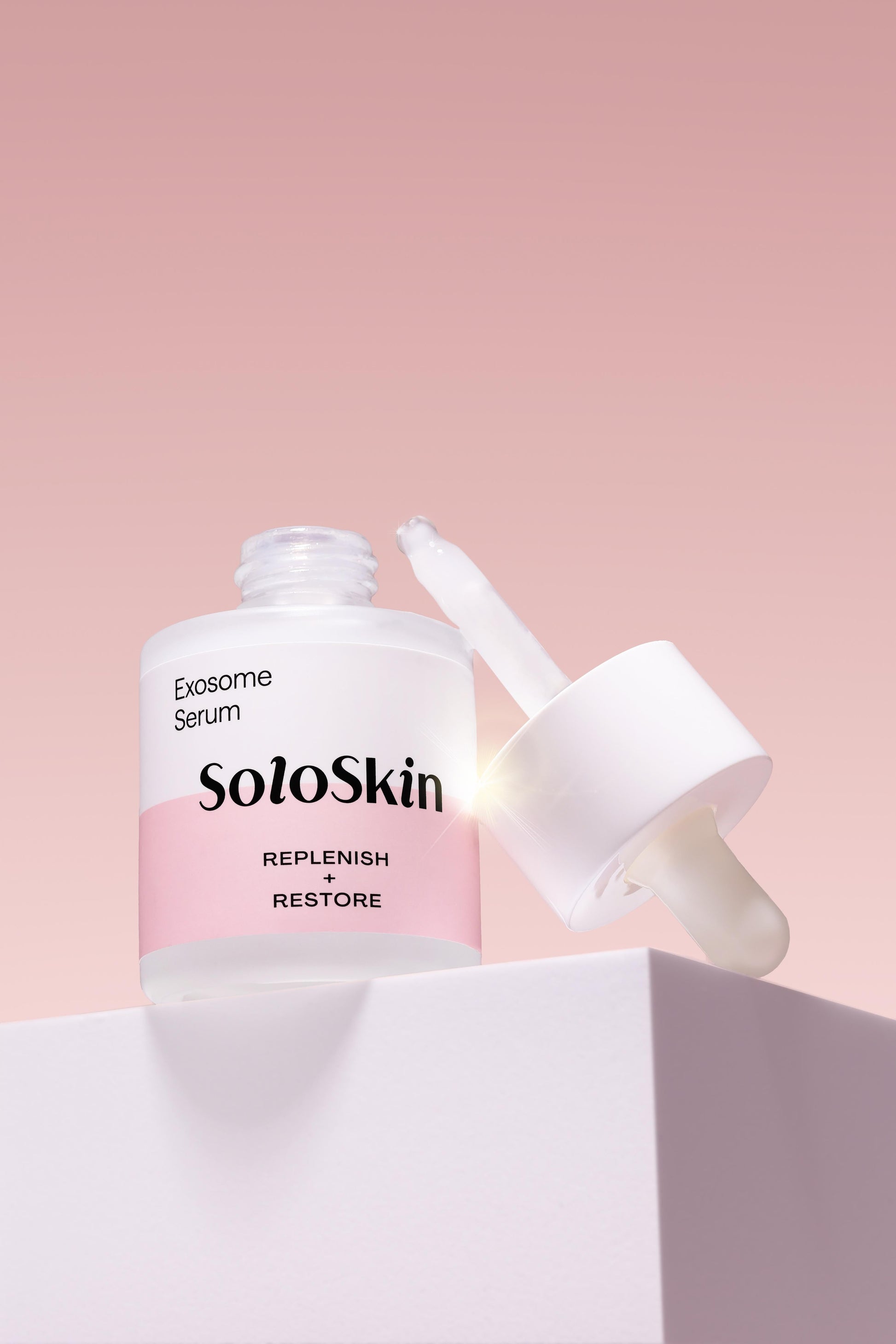 SoloSkin Exosome Serum bottle with dropper on a pink background