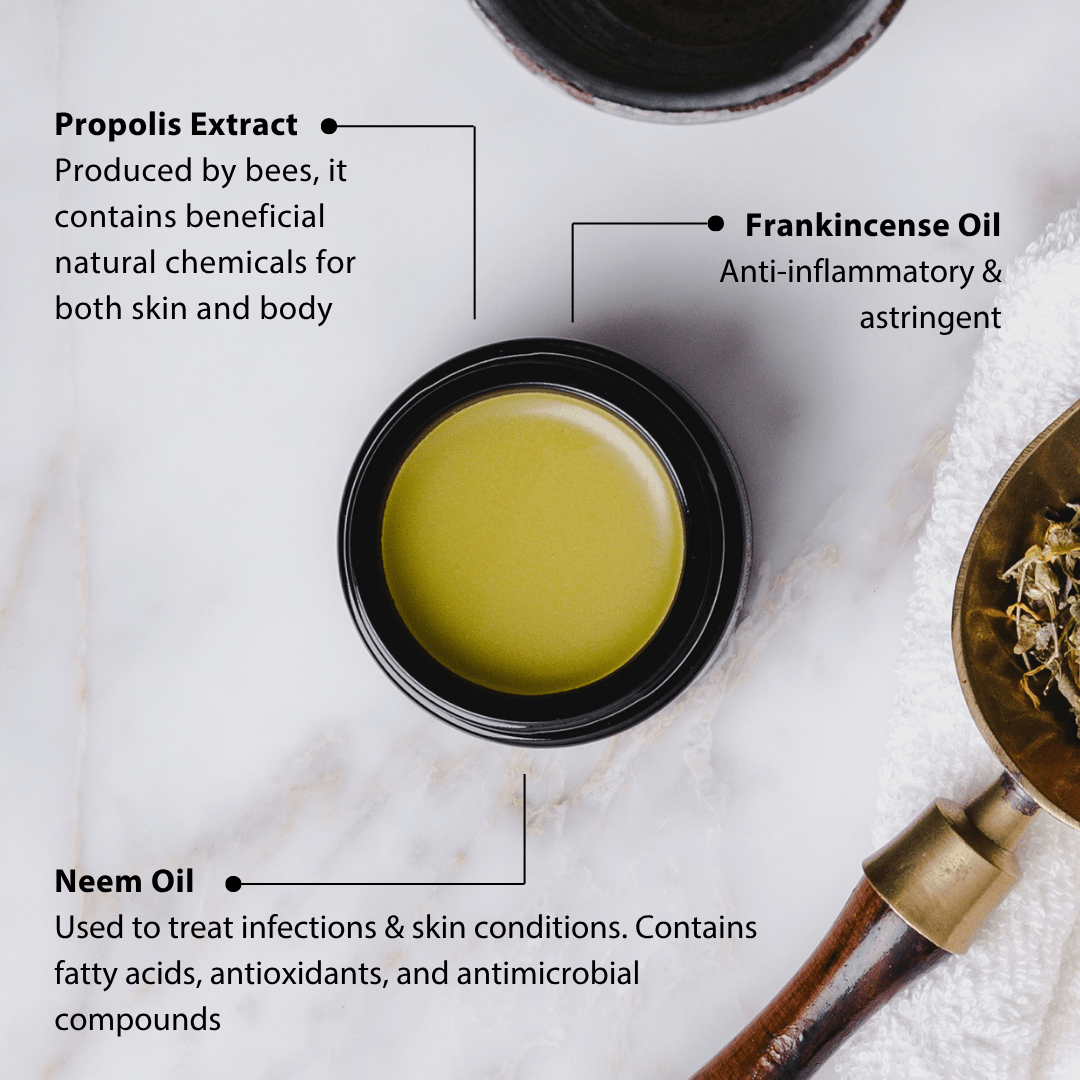 Green oil in a black container with text about propolis extract, frankincense oil, and neem oil on a white marble background.