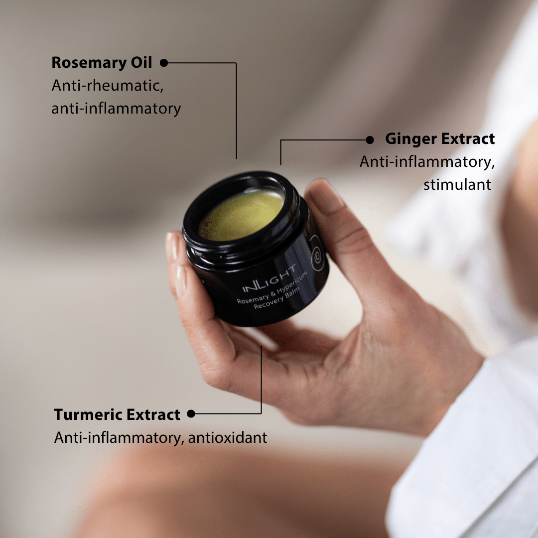 Hand holding a jar of Inlight Beauty Rosemary & Hypericum Recovery Balm 45ml with labeled ingredients on a blurred background