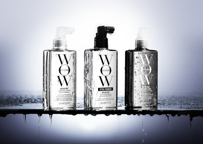 Three WOW Skin & Beauty shower gel bottles lined up on a reflective wet surface with water droplets and dripping water. The bottles are clear with white and black text, set against a cool blue-gray gradient background.