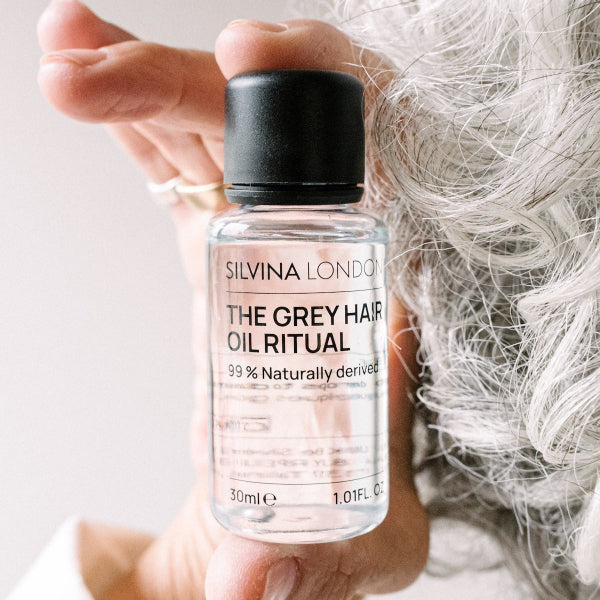 Bottle of Silvina London Grey Hair Oil Ritual held by a hand with grey hair.