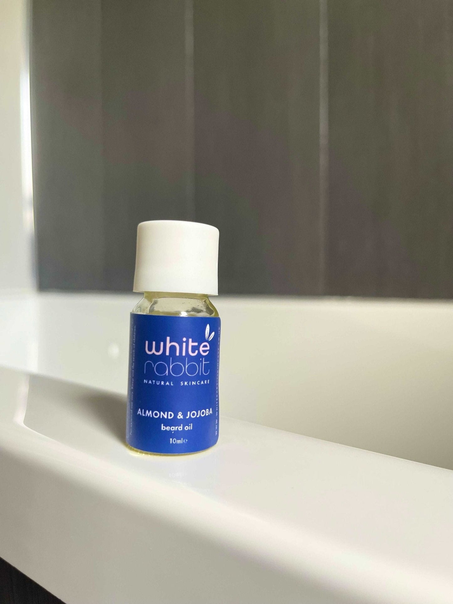 White Rabbit almond and jojoba hair oil bottle on a white surface with a neutral background