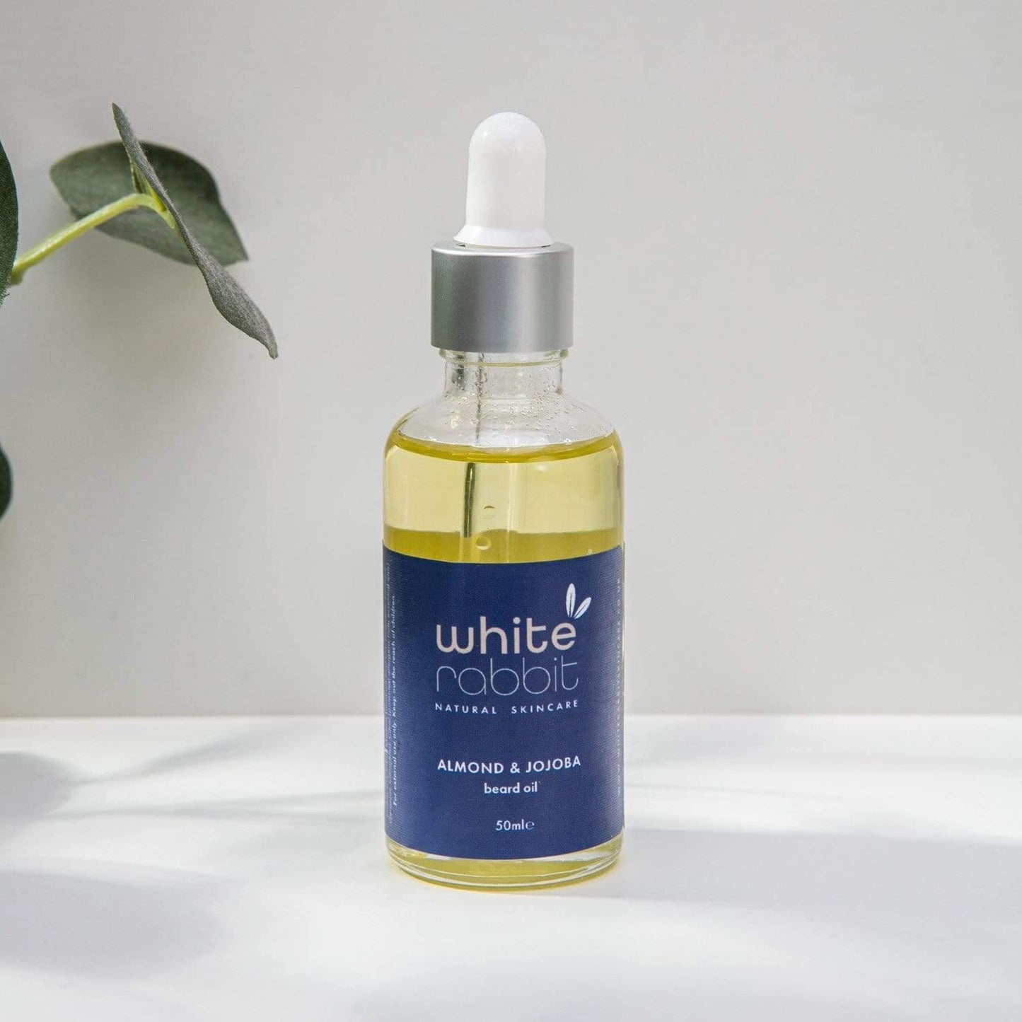 Bottle of White Rabbit skincare oil with a dropper on a white surface.