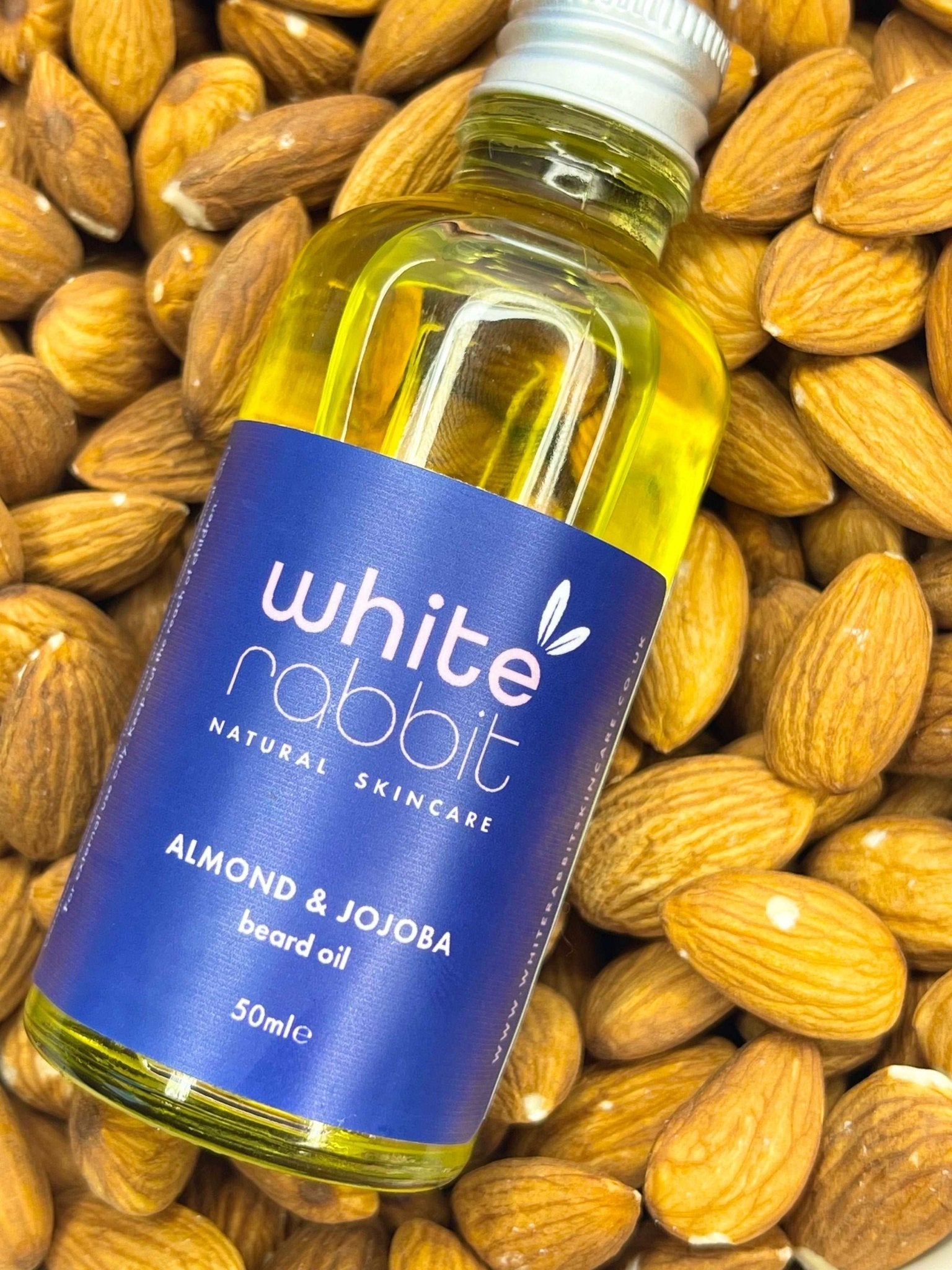 Bottle of White Rabbit Almond & Jojoba beard oil surrounded by almonds