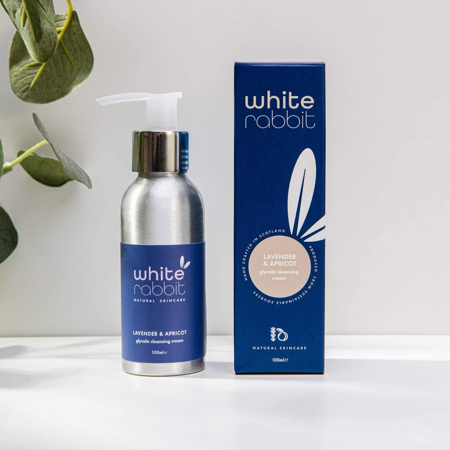 White Rabbit skincare bottle and packaging on a white surface with a plant in the background