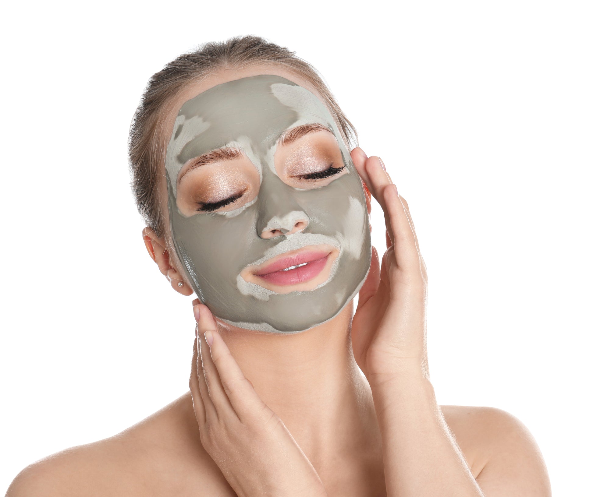 Woman applying a green facial mask on a white background