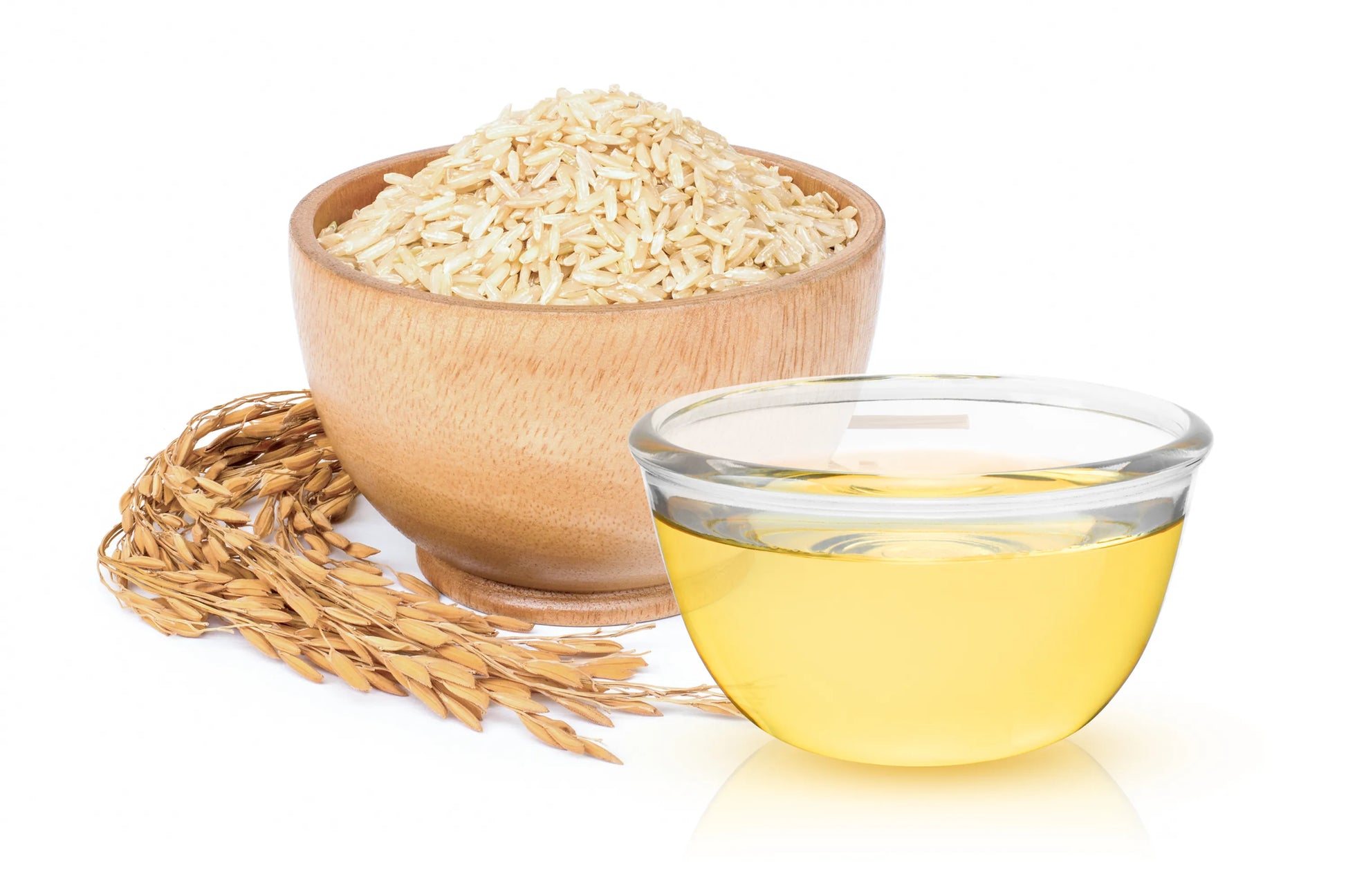 Wooden bowl of rice and glass container of rice oil on a white background