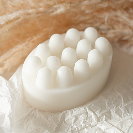 White silicone scrubber soap bar on a textured surface with a soft beige background
