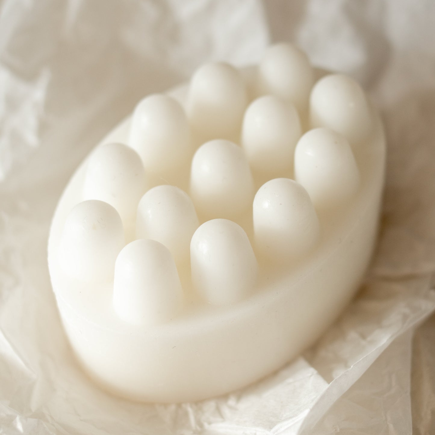 Close-up of a white scrubber-type soap bar on a soft beige background