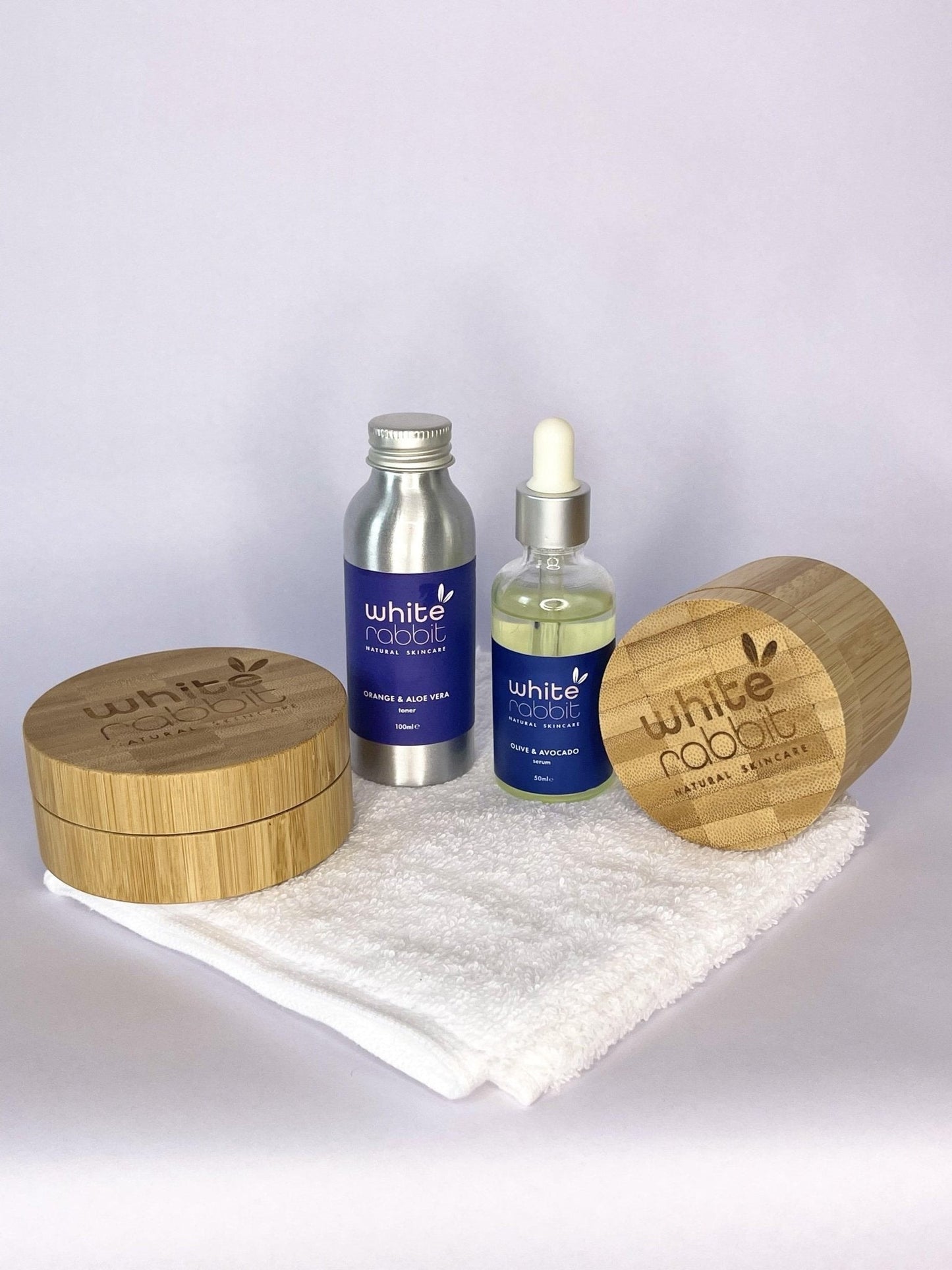 Skincare products with wooden containers and a towel on a white background