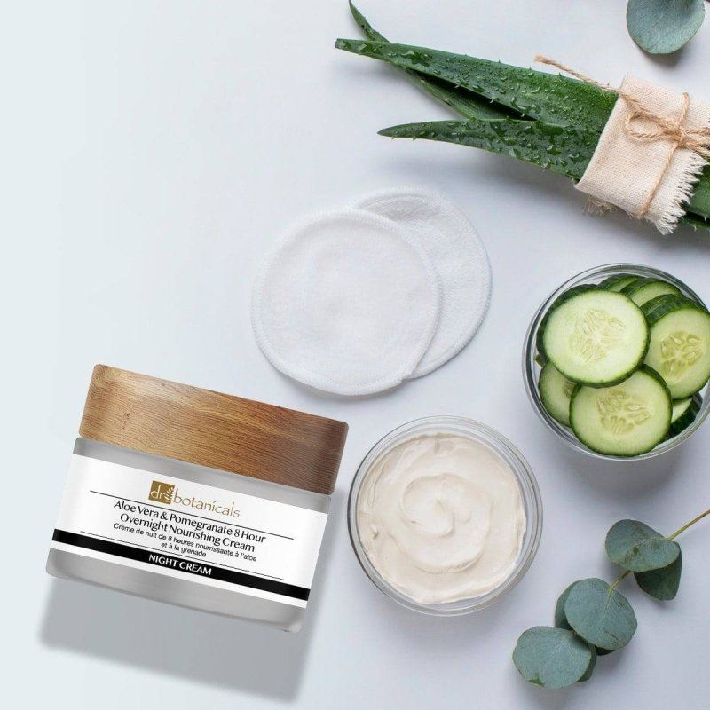 Cosmetic jar with aloe vera, cucumbers, and eucalyptus leaves on a light background