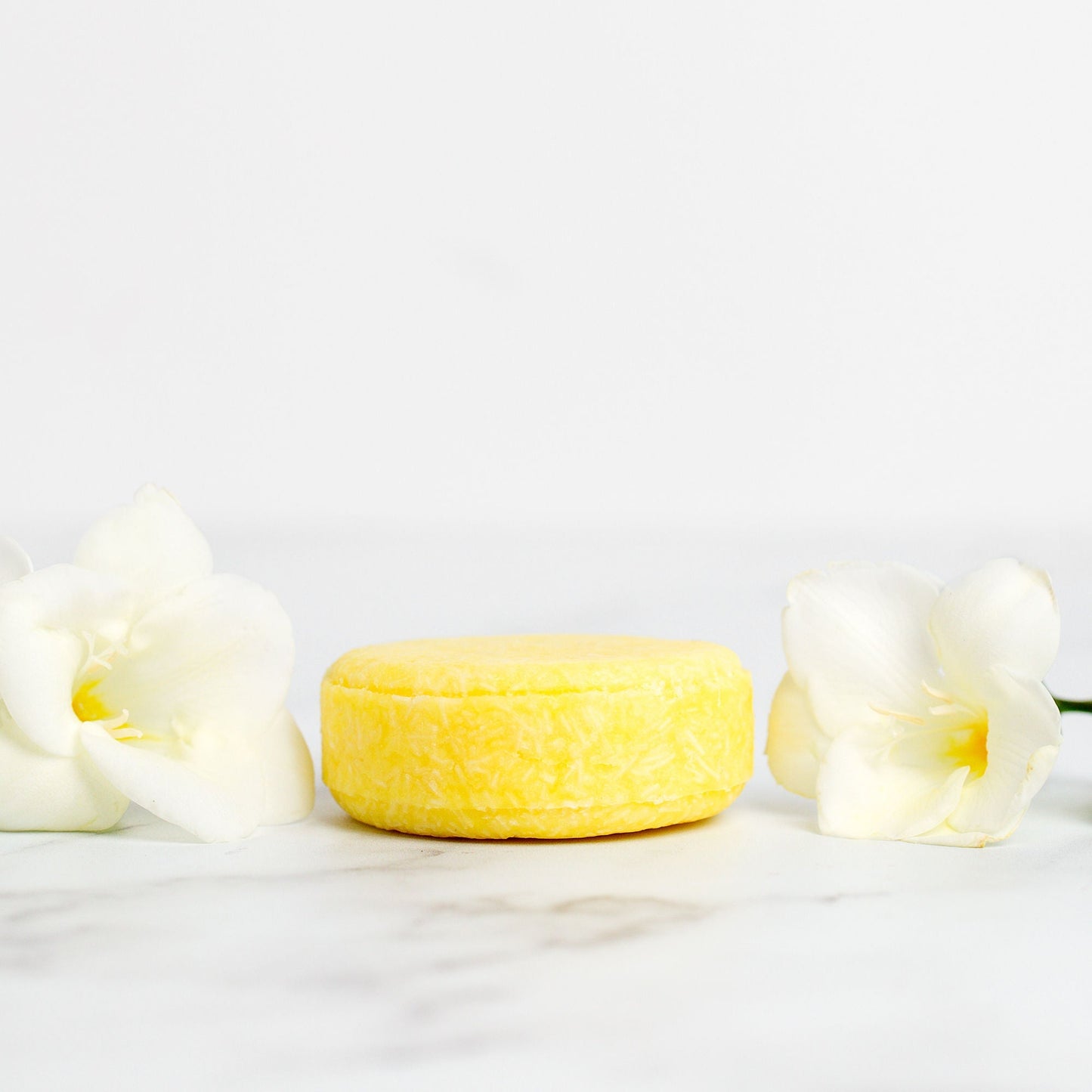 Yellow soap bar with white freesias on a light background