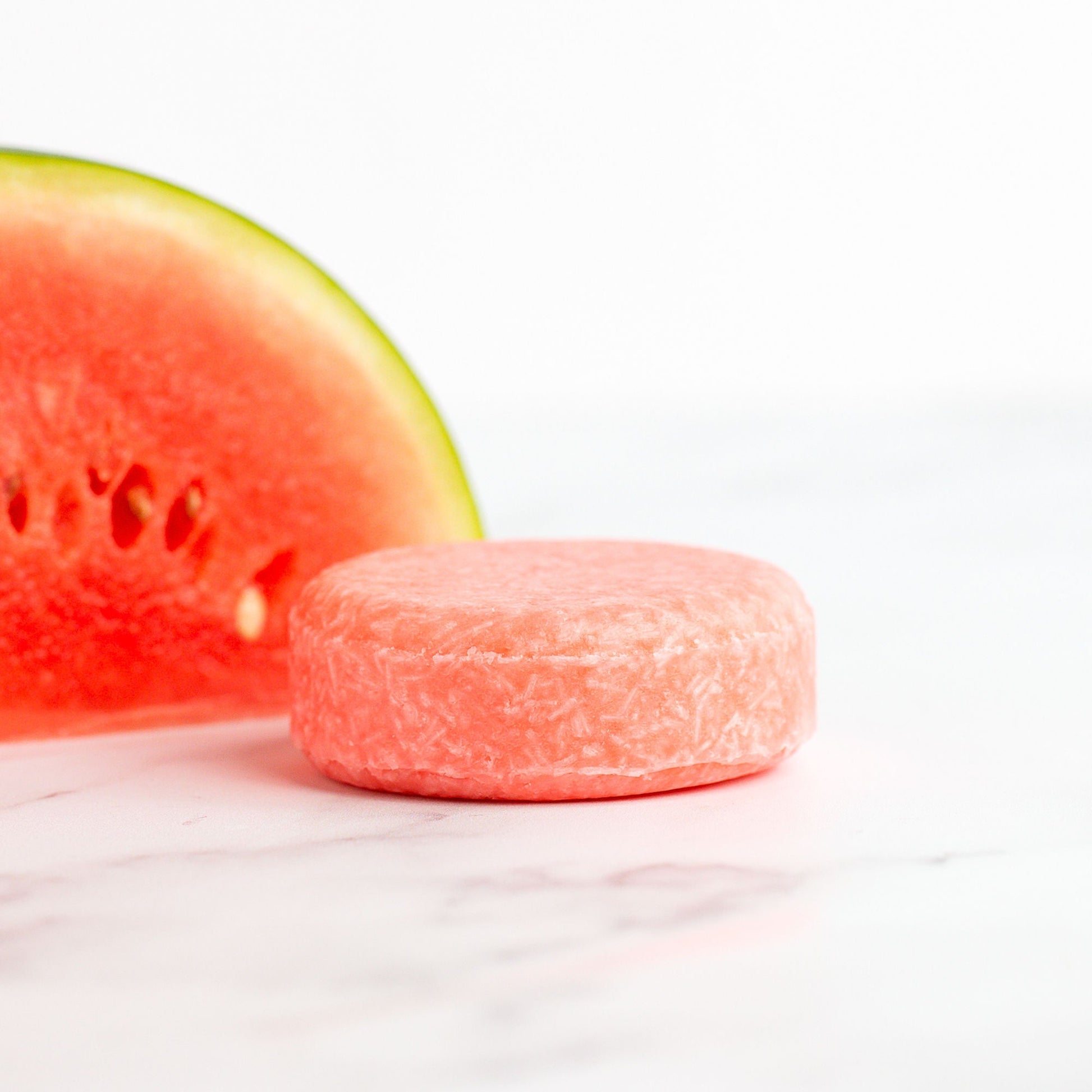 Pink candy next to a slice of watermelon on a white background