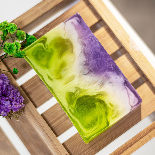 Colourful soap bar with green and purple swirls on a wooden surface.