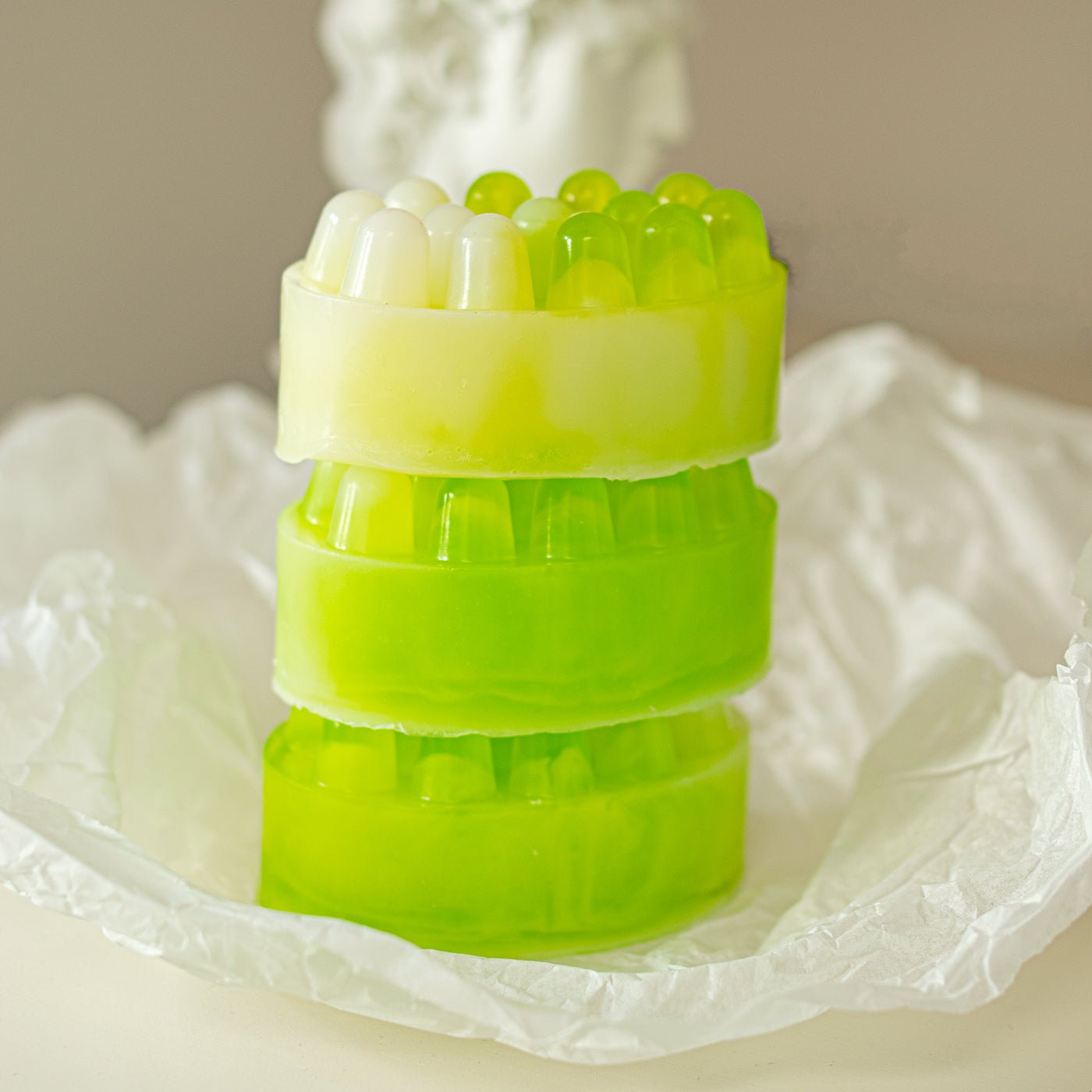 Stack of green soap bars with textured tops on a white surface
